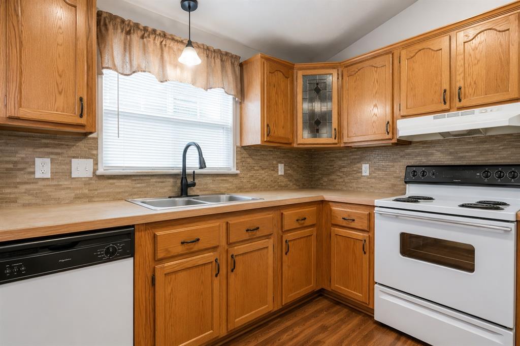 9455 Tranquil Acres Road Fort Worth, TX 76179 - Photo 5 of 20 Kitchen featuring wood cabinetry, a double basin stainless steel sink with a matte black faucet, a textured tile backsplash, and wood-finish flooring