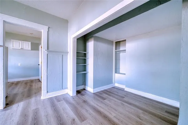 a view of an empty room with wooden floor and closet