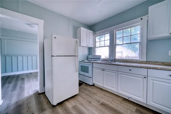 a kitchen with granite countertop white cabinets and white appliances