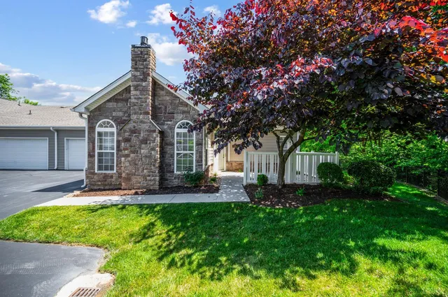 a front view of a house with a yard and trees