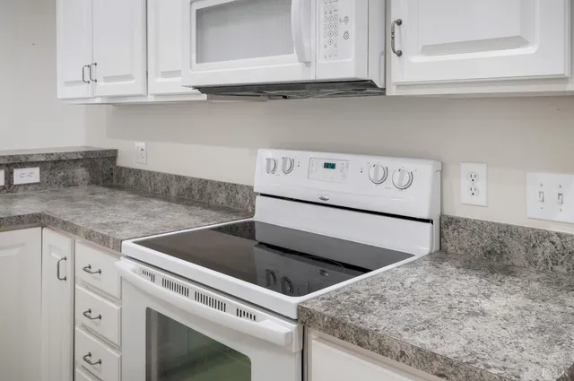 a kitchen with granite countertop white cabinets and white appliances