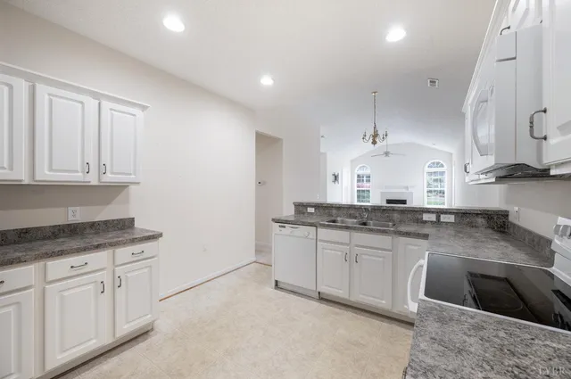 a kitchen with granite countertop a sink a stove and cabinets
