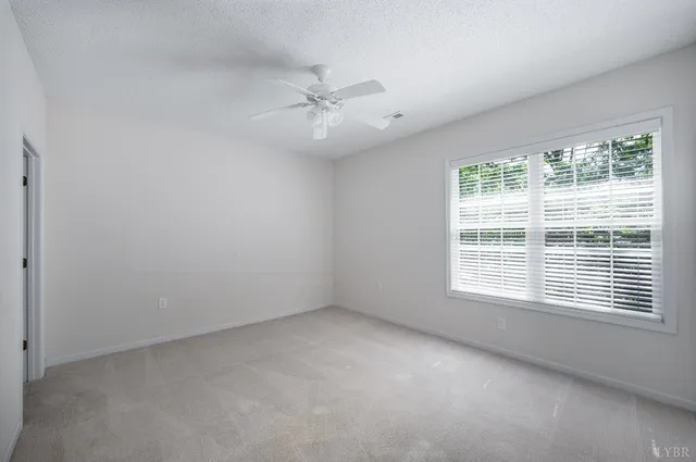 an empty room with a window and a fan