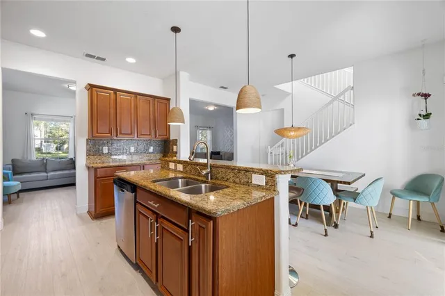 a kitchen with stainless steel appliances granite countertop a sink a stove and a wooden cabinets