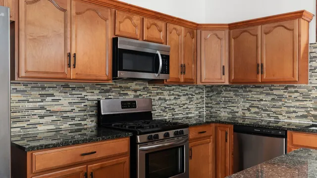 a kitchen with stainless steel appliances granite countertop a stove top oven microwave and cabinets