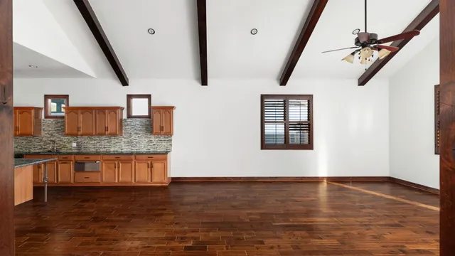 a view of an empty room with kitchen and a window