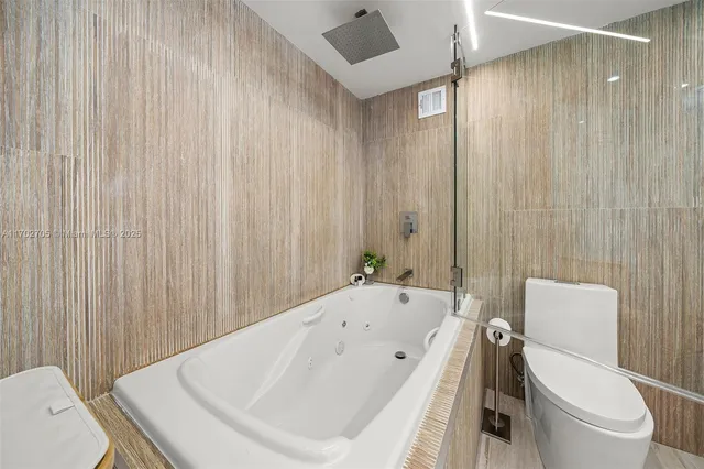 a white bath tub sitting next to a white toilet and curtain