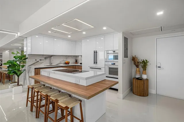 a living room with furniture a potted plant and kitchen view