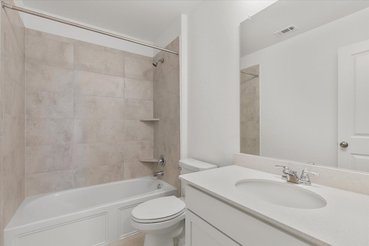 101 Rowdy Yates Way Jarrell, TX 76537 - Photo 26 of 32 Bathroom featuring a single vanity with an integrated sink, a large wall-mounted mirror, and a toilet