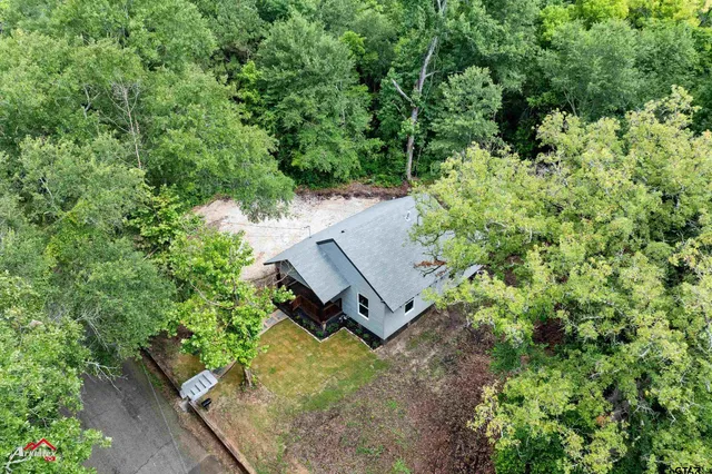 an aerial view of a house with a yard and large trees