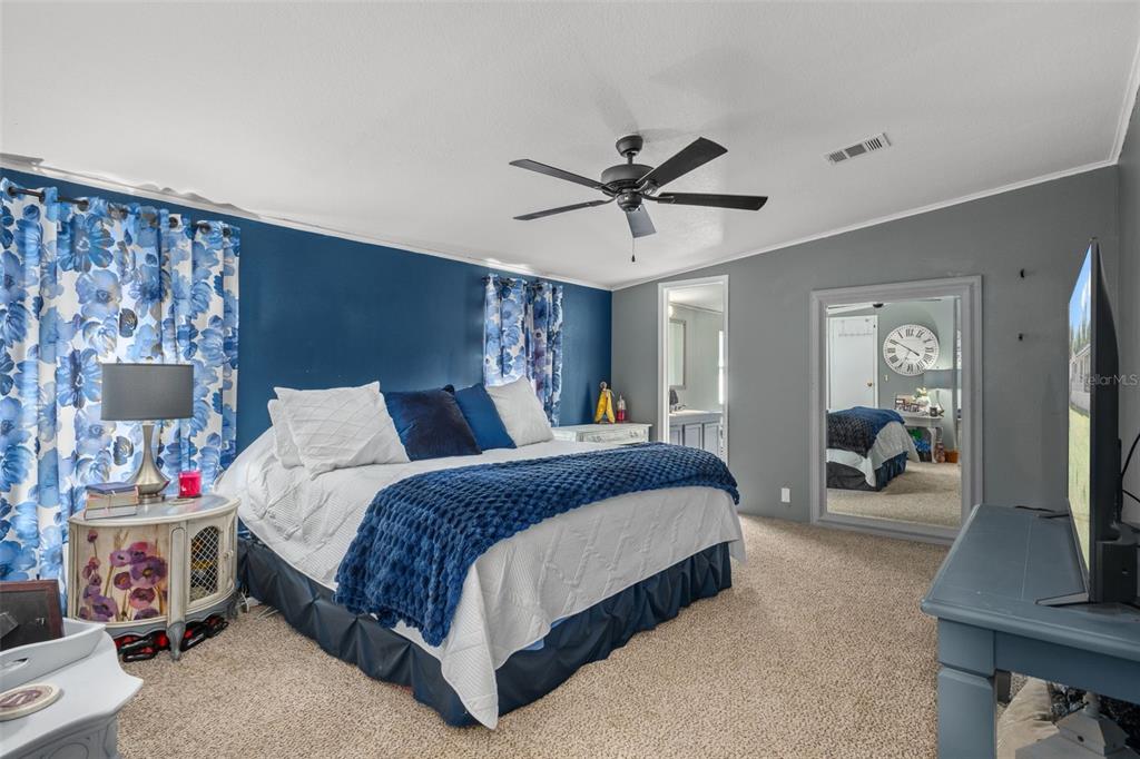 460 Korbus Road Brooksville, FL 34604 - Photo 13 of 22 a spacious bedroom with a bed a mirror and a flat tv screen on dresser