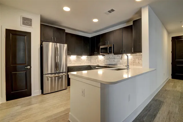 a kitchen with kitchen island a refrigerator and a sink