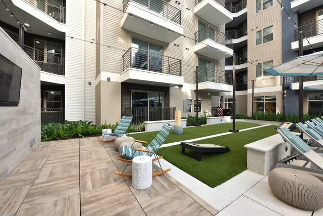 a living room with couches a flat screen tv and kitchen view