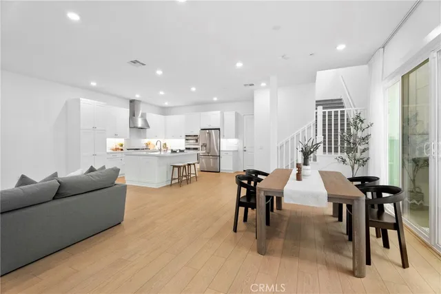 a living room kitchen with a dining table wooden floor and a kitchen view