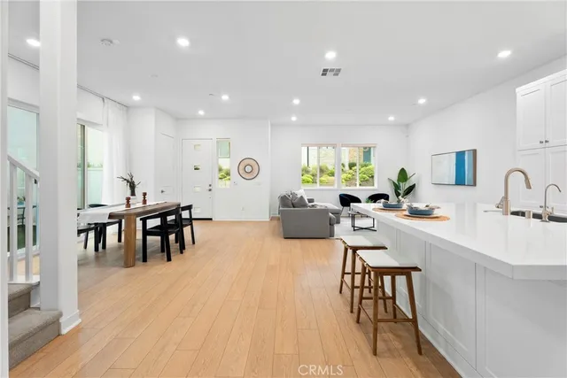 a living room with furniture a wooden floor and a kitchen view