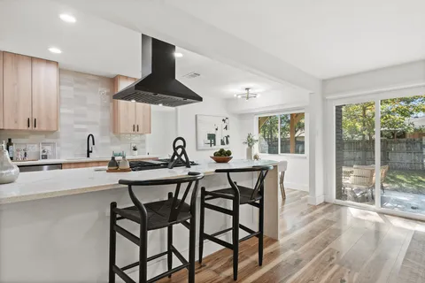 a kitchen with stainless steel appliances a dining table chairs and a large window