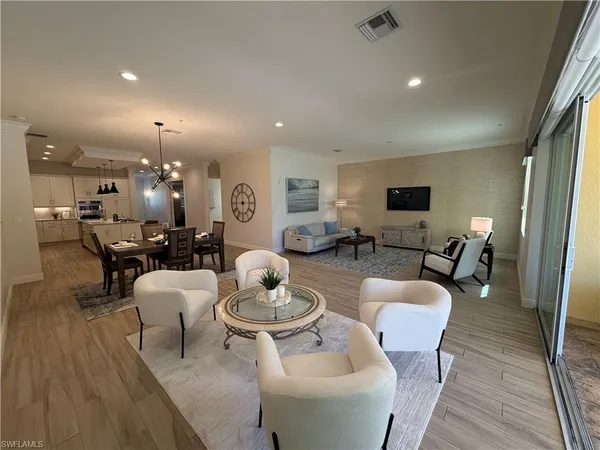 a living room with furniture kitchen view and a wooden floor