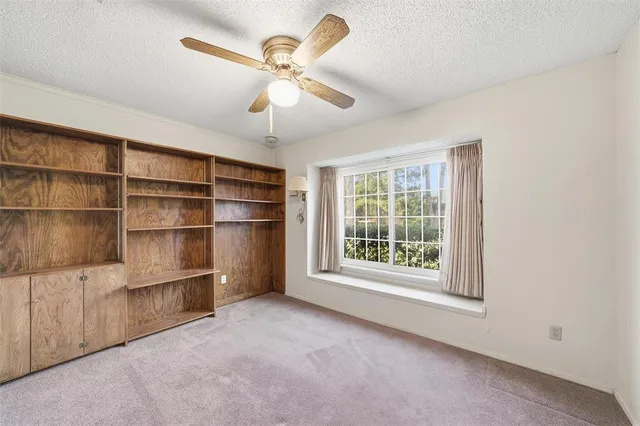 a view of an empty room with a window and cabinet
