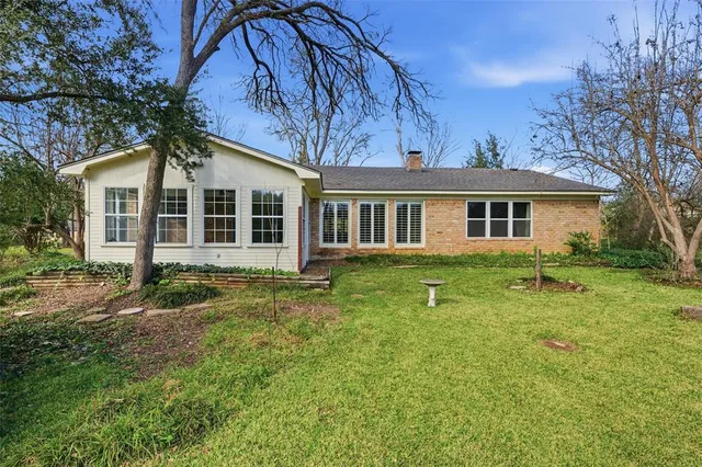 a view of a yard in front of a house with large windows