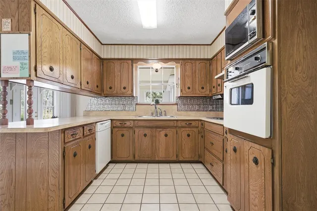 a large kitchen with stainless steel appliances granite countertop a sink and dishwasher a oven with wooden cabinets