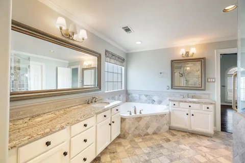 a bathroom with a granite countertop double vanity sink a mirror and a bathtub