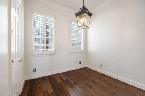 an empty room with wooden floor cabinet and windows