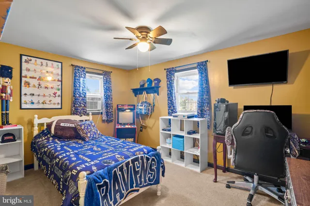 a bedroom with a bed a computer on the desk and a book shelf