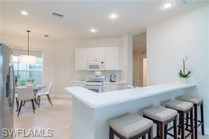 9271 Museo Circle, Unit 102 Naples, FL 34114 - Photo 5 of 13 a kitchen with a table chairs sink and cabinets