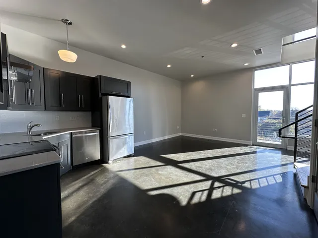 a kitchen with granite countertop a stove a sink dishwasher a refrigerator and wooden cabinets with wooden floor