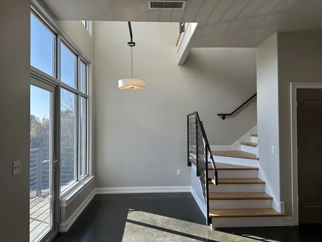a view of staircase with lots of frames on wall and a window