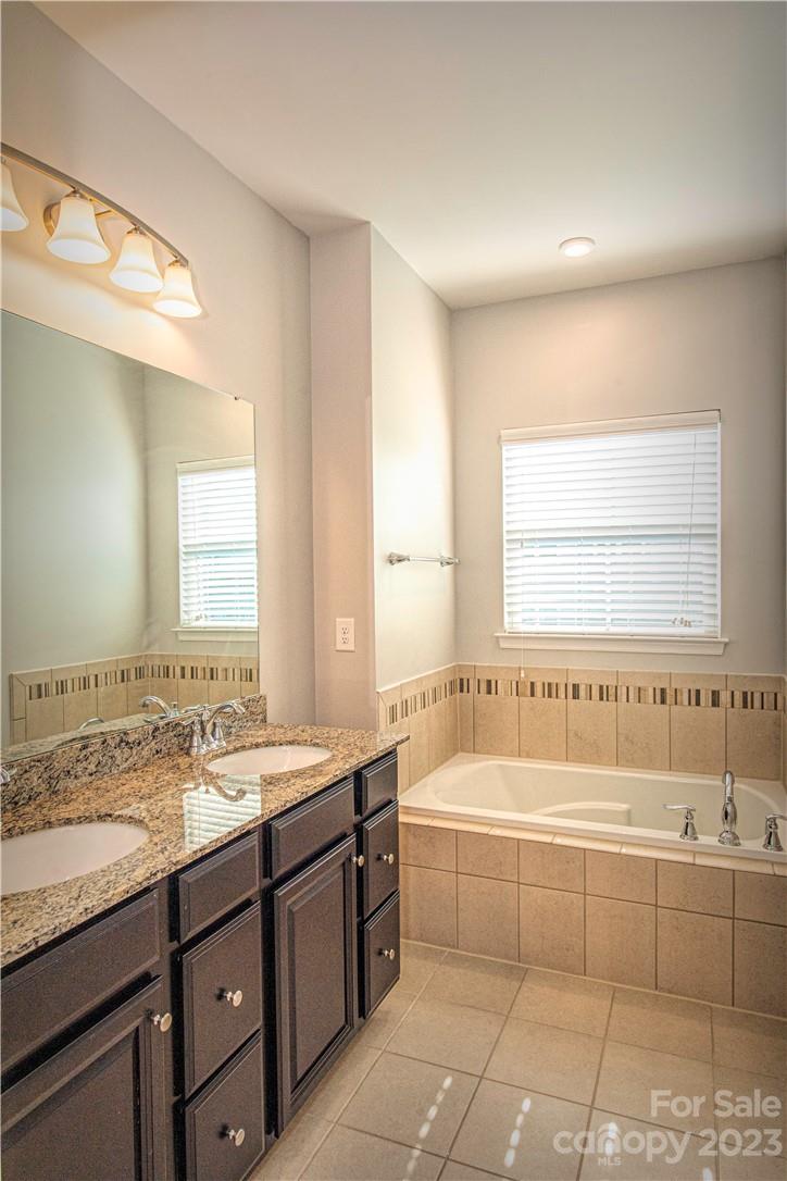 12725 Glowing Peak Road Huntersville, NC 28078 - Photo 8 of 17 a bathroom with a granite countertop bathtub a sink and a window
