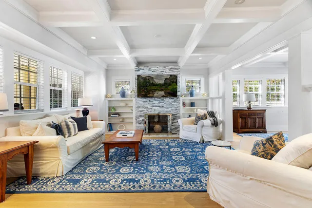 a living room with furniture a fireplace a flat screen tv and a large window