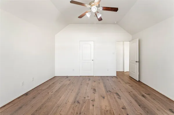 an empty room with wooden floor closet and windows