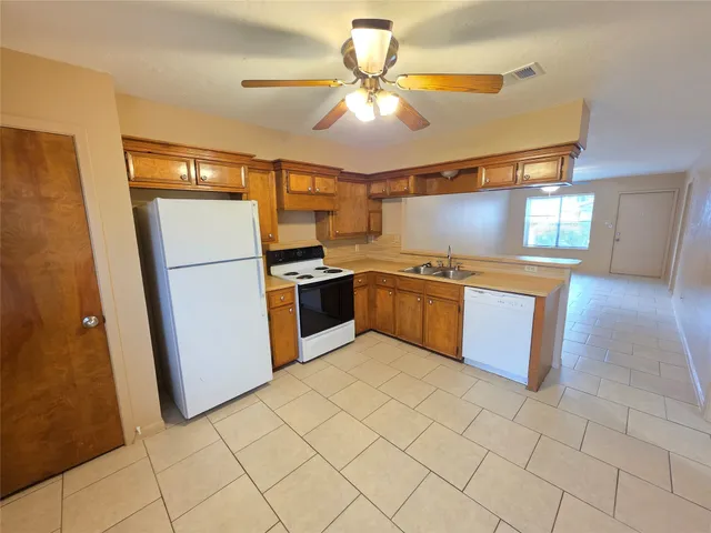 a kitchen with stainless steel appliances granite countertop a refrigerator a sink a stove top oven and cabinets