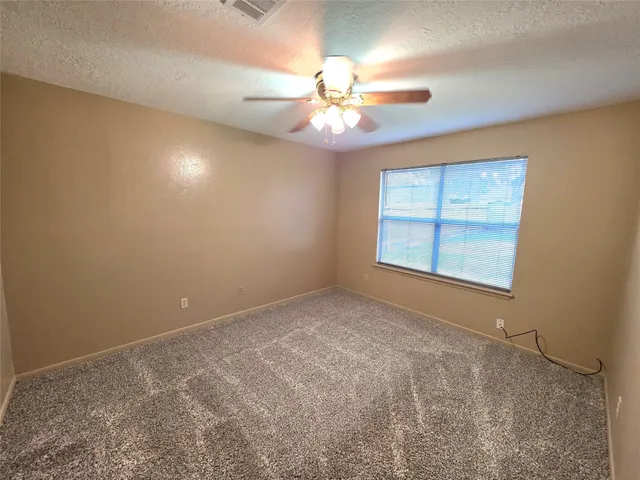 an empty room with windows and fan