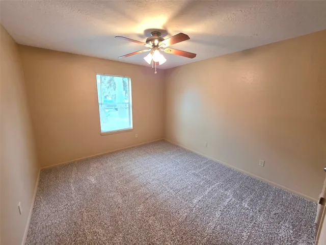 an empty room with windows and chandelier fan