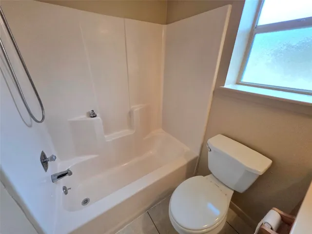 a white toilet sitting next to a bath tub