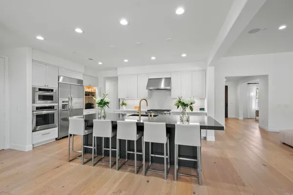 a kitchen with stainless steel appliances granite countertop a dining table chairs sink and cabinets