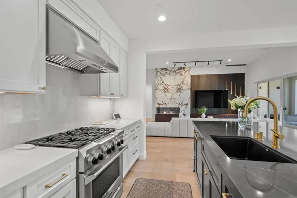 a kitchen with stainless steel appliances granite countertop a refrigerator a stove and a sink with wooden floor