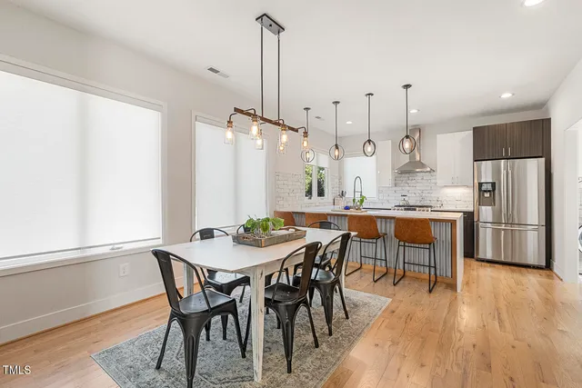a view of a dining room and livingroom with furniture wooden floor a chandelier