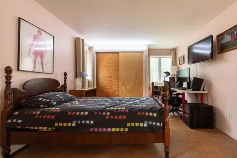 a bedroom with a bed window and a flat screen tv