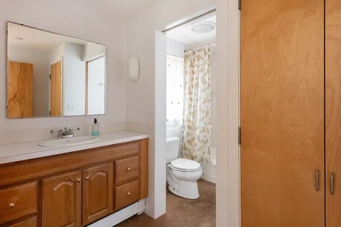 a bathroom with a granite countertop sink a toilet and a mirror