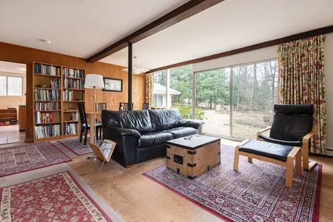 a living room with furniture a rug and a floor to ceiling window