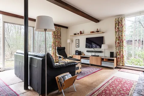 a living room with furniture a flat screen tv and a floor to ceiling window