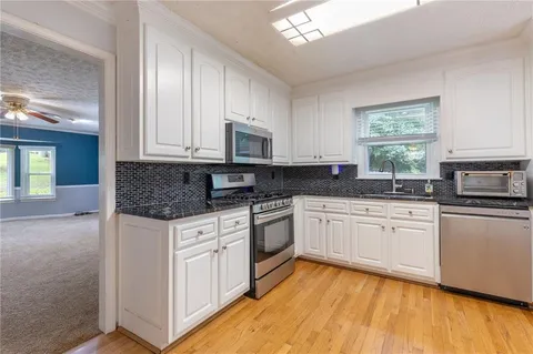 a kitchen with cabinets stainless steel appliances and wooden floor
