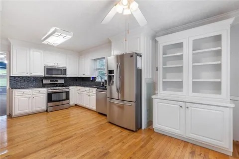 a kitchen with stainless steel appliances granite countertop a stove a refrigerator a sink and dishwasher with wooden floor