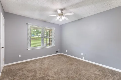an empty room with a chandelier fan and windows