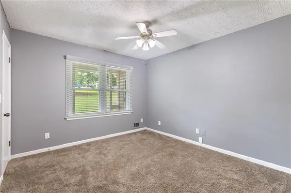 an empty room with a chandelier fan and windows