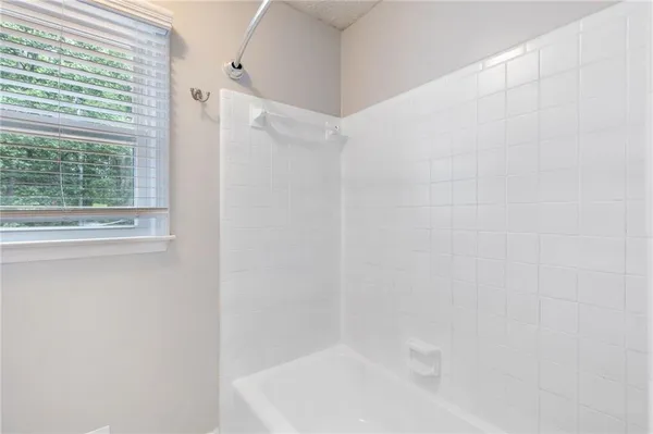 an empty room with a chandelier fan and windows