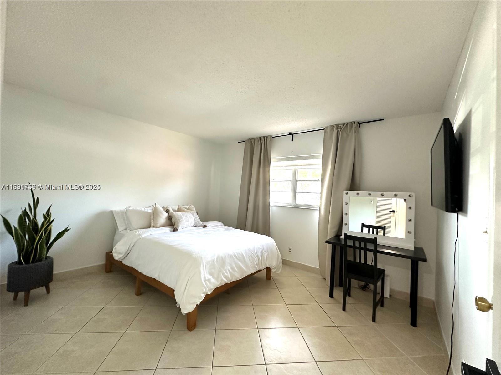 620 Northeast 12th Avenue, Unit 102 Hallandale Beach, FL 33009 - Photo 18 of 23 a bedroom with a bed and a mirror